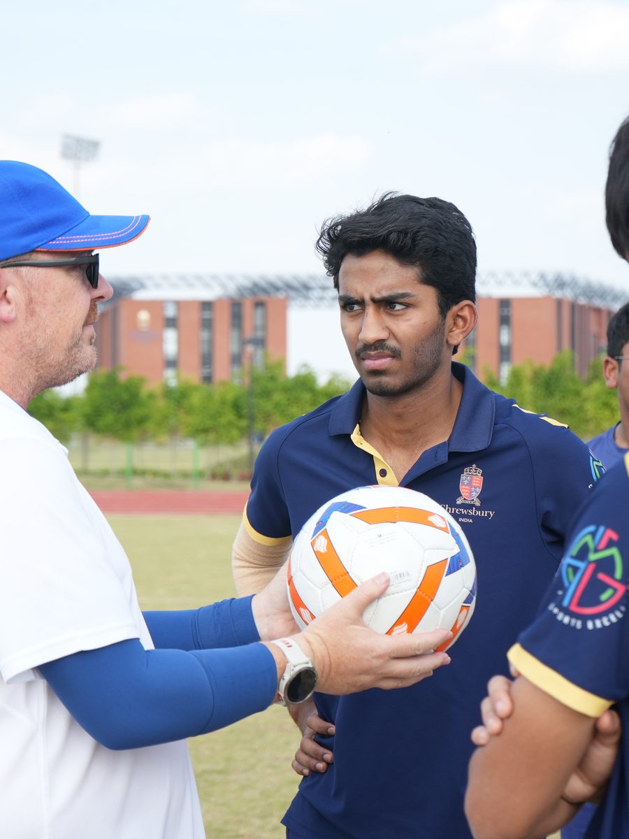 A coach and a pupil talking on the sports field
